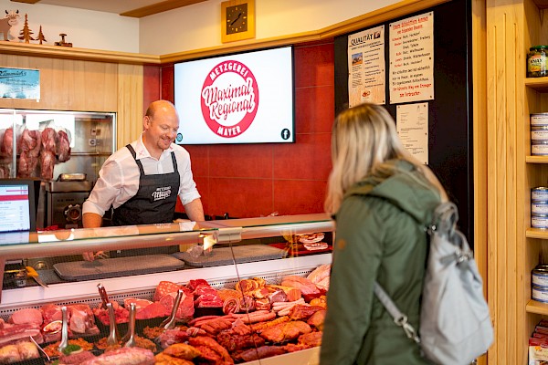 Frank Mayer steht hinter der Fleischtheke und bedient eine Kundin.