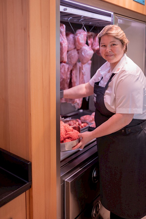 Das Bild zeigt Bettina Fichtel an der Wolfmaschine in der Filiale. Dabei lächelt sie in die Kamera.