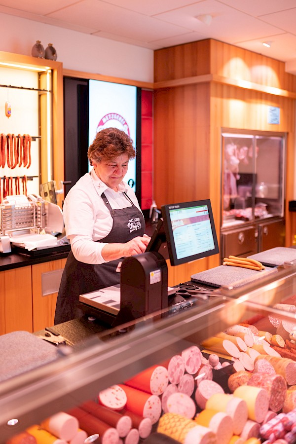 Eine Verkäuferin tippt ein Produkt in die Waage ein.