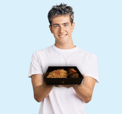 Ein Mann hält ein Essen in einem Mehrwegbehälter in der Hand und lächelt in die Kamera.