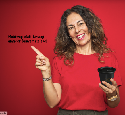 Eine Frau lächelt in die Kamera und zeigt auf einen Spruch.